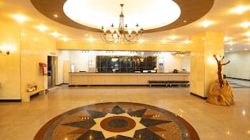 Un vestíbulo amplio con una lámpara central, una recepción y un suelo decorado con motivos de estrellas.