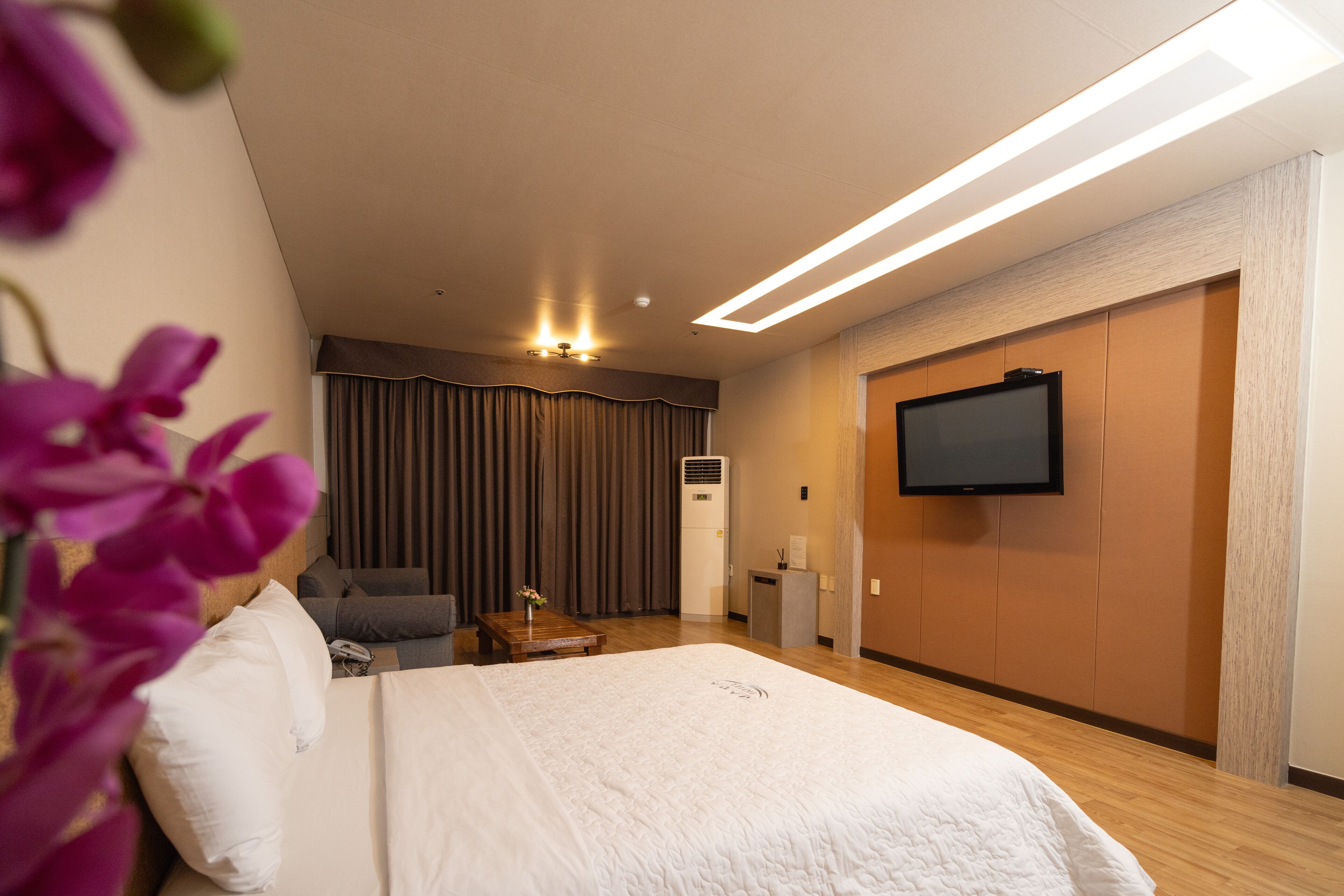 Habitación de hotel con una cama grande, un televisor de pantalla plana montado en la pared, un escritorio con una silla y una ventana con cortinas.