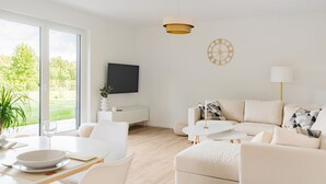 A modern living room with a sofa, a coffee table, and a dining table set for two. - Ferienwohnung Zur Örtze (Faßberg)