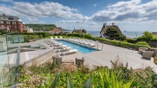 Un espace piscine aménagé sur le toit, avec des chaises longues et une vue dégagée sur la mer.