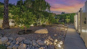Un jardín ajardinado con un sendero, árboles y un edificio de diseño moderno.