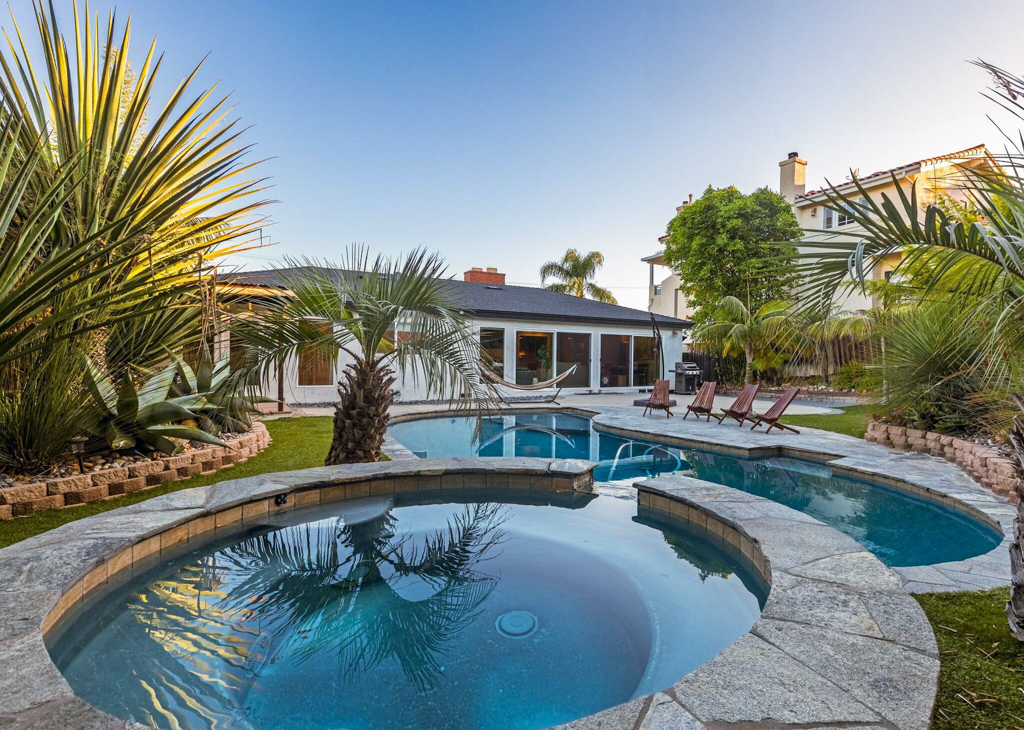 A pool area with a house in the background.