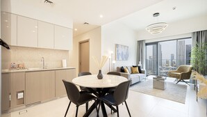 A modern kitchen with a round dining table, black chairs, and a city view through large windows.