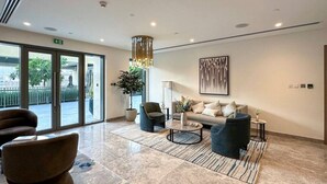 Un hall d’entrée moderne avec un canapé, des fauteuils, une table basse et une plante en pot.