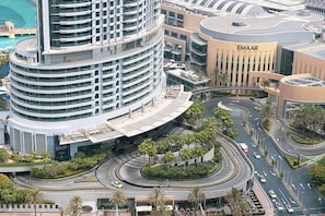 A multi-story hotel with a curved facade, a central atrium, and a landscaped area with palm trees.