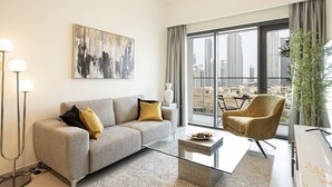 A modern living room with a sofa, armchair, and coffee table, large windows with a city view, and a floor lamp.