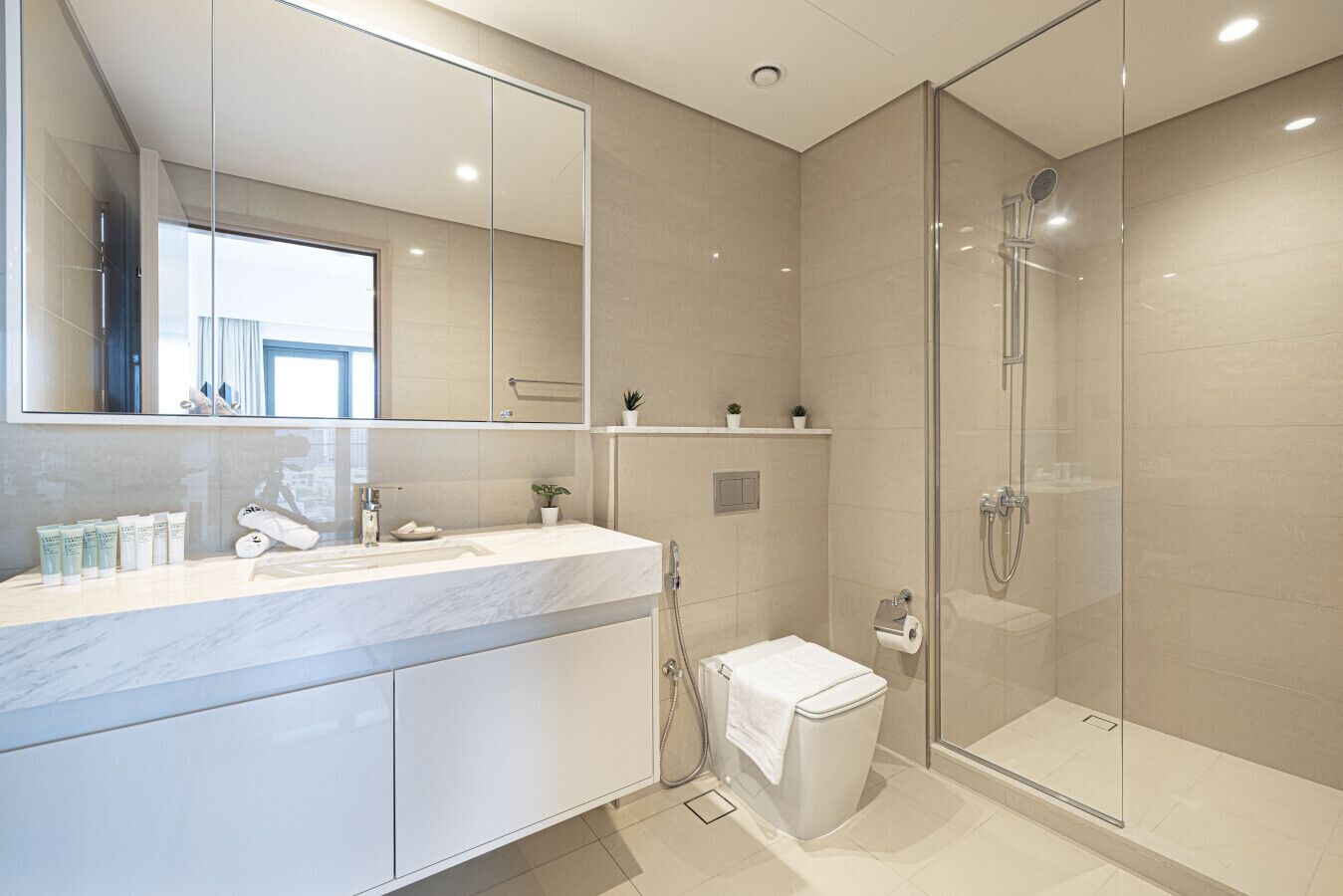 Une salle de bain moderne avec une douche à parois de verre, un grand miroir et un plan de toilette en marbre.
