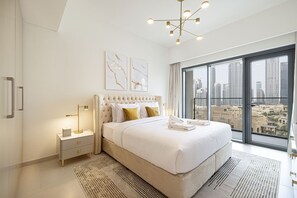 A modern bedroom with a large bed, a nightstand, a lamp, and a view of the city through large windows.