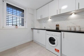 Enjoy cooking in this well-equipped kitchen with a washing machine, window, and tiled backsplash.