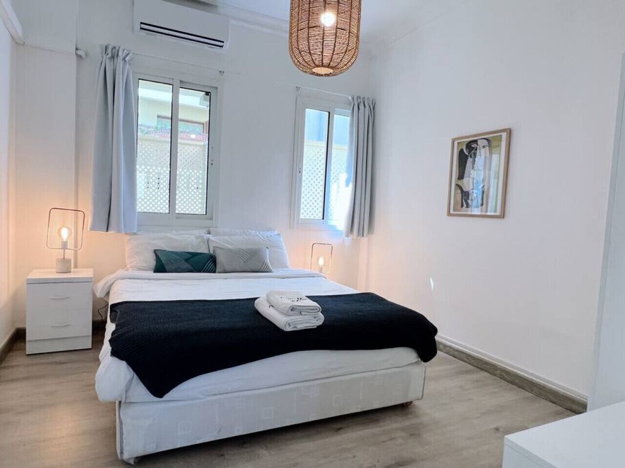 A modern bedroom with a bed, bedside tables, and a hanging light fixture.