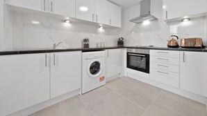 A modern kitchen with white cabinets, a built-in washing machine, an oven, and a toaster. - Serviced Ensuite Room Crystal Palace London Se20 (London)