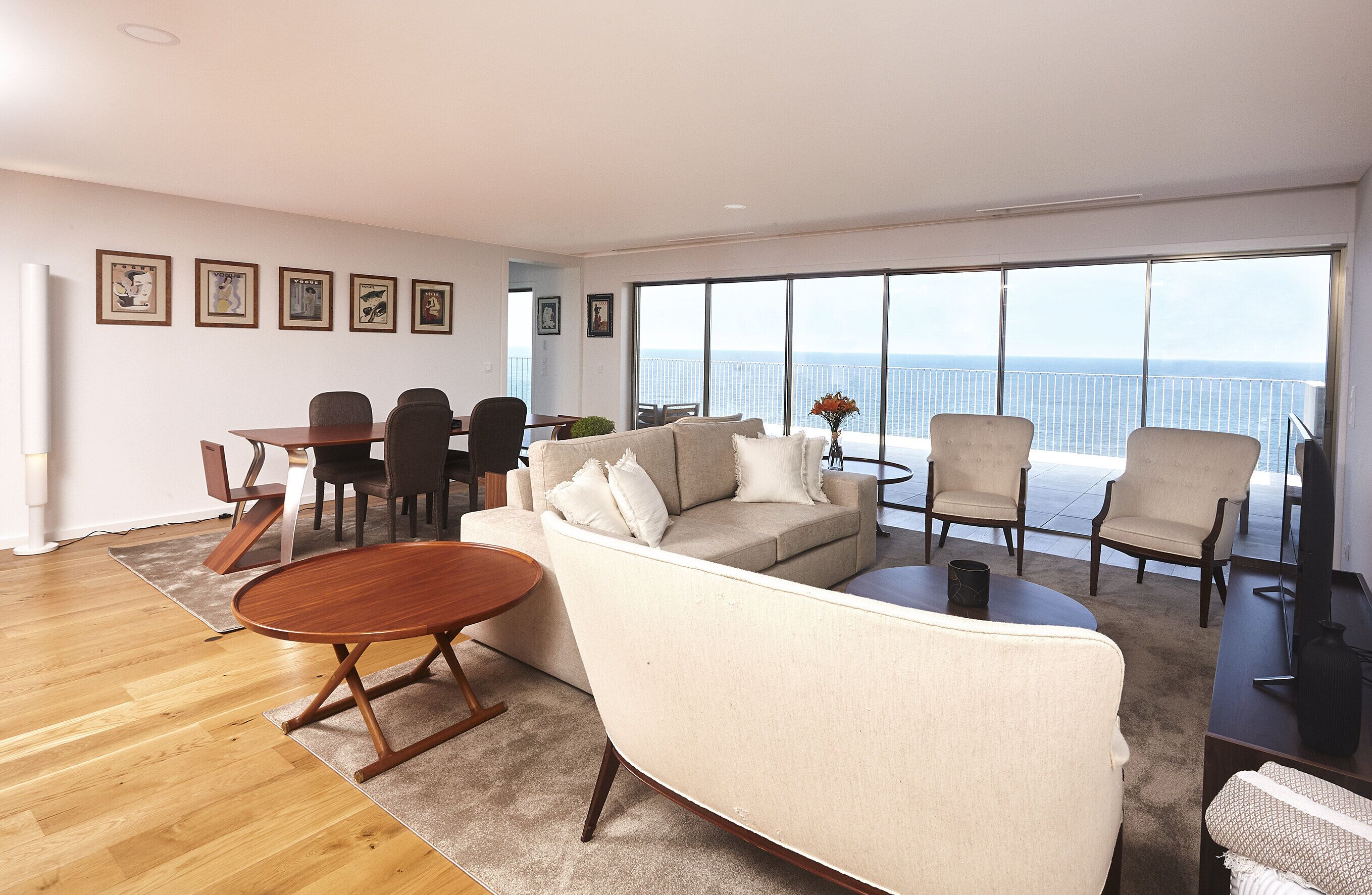 Un salón amplio con un gran ventanal, un sofá, una mesa de centro y una zona de comedor con sillas y una mesa.