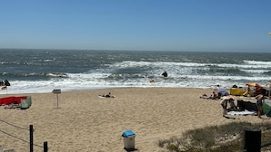 A beach with people sunbathing and a flag on the sand. - Porto Ocean Flat (Vila Nova de Gaia)