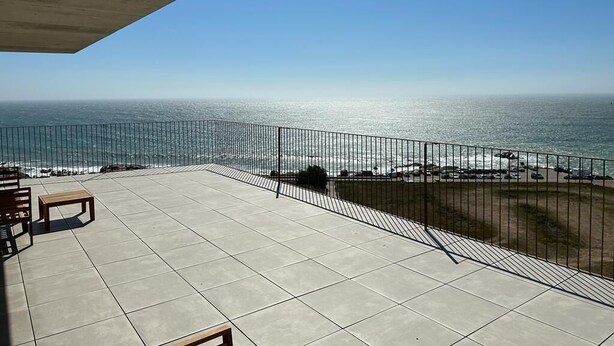 A balcony with a view of the ocean, a railing, and a few chairs and a table. - Porto Ocean Flat (Vila Nova de Gaia)