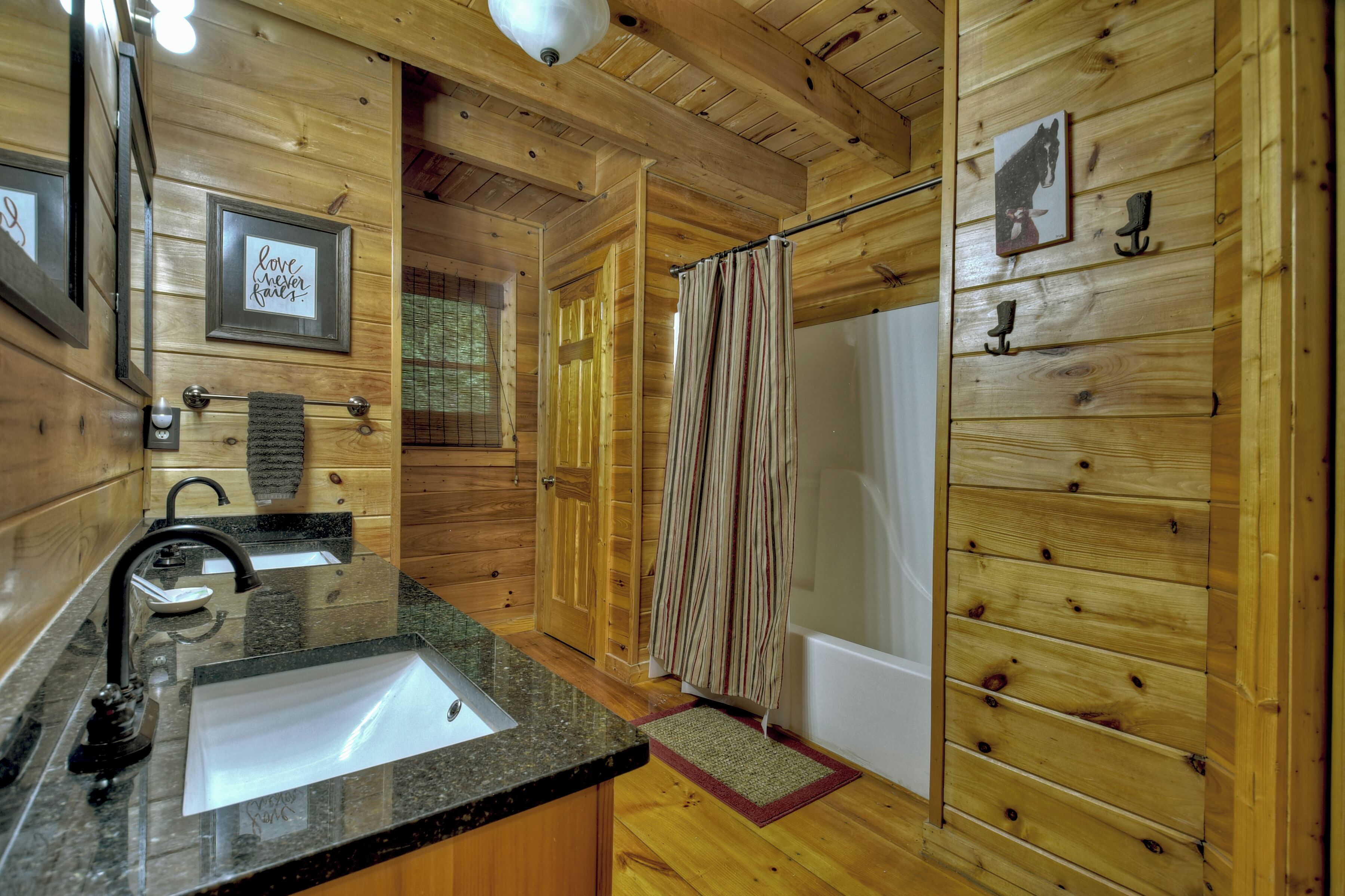 Une salle de bain rustique, aménagée dans une cabane en bois, avec un lavabo, un miroir, un porte-serviettes et un rideau de douche.