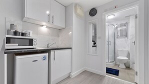 A modern kitchen with white cabinets, a microwave, and a mini-fridge.