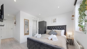 Quarto moderno com cama grande, cabeceira escura e mesa de cabeceira com abajur.