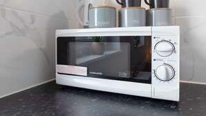 Eine weiße Mikrowelle mit digitalem Display und Bedienelementen auf einer schwarzen Arbeitsplatte.