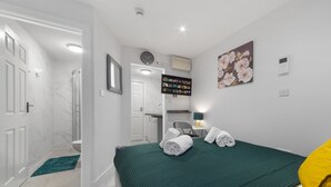 Ein Hotelzimmer mit Bett, Schreibtisch, Stuhl, Bad und Wandklimaanlage.