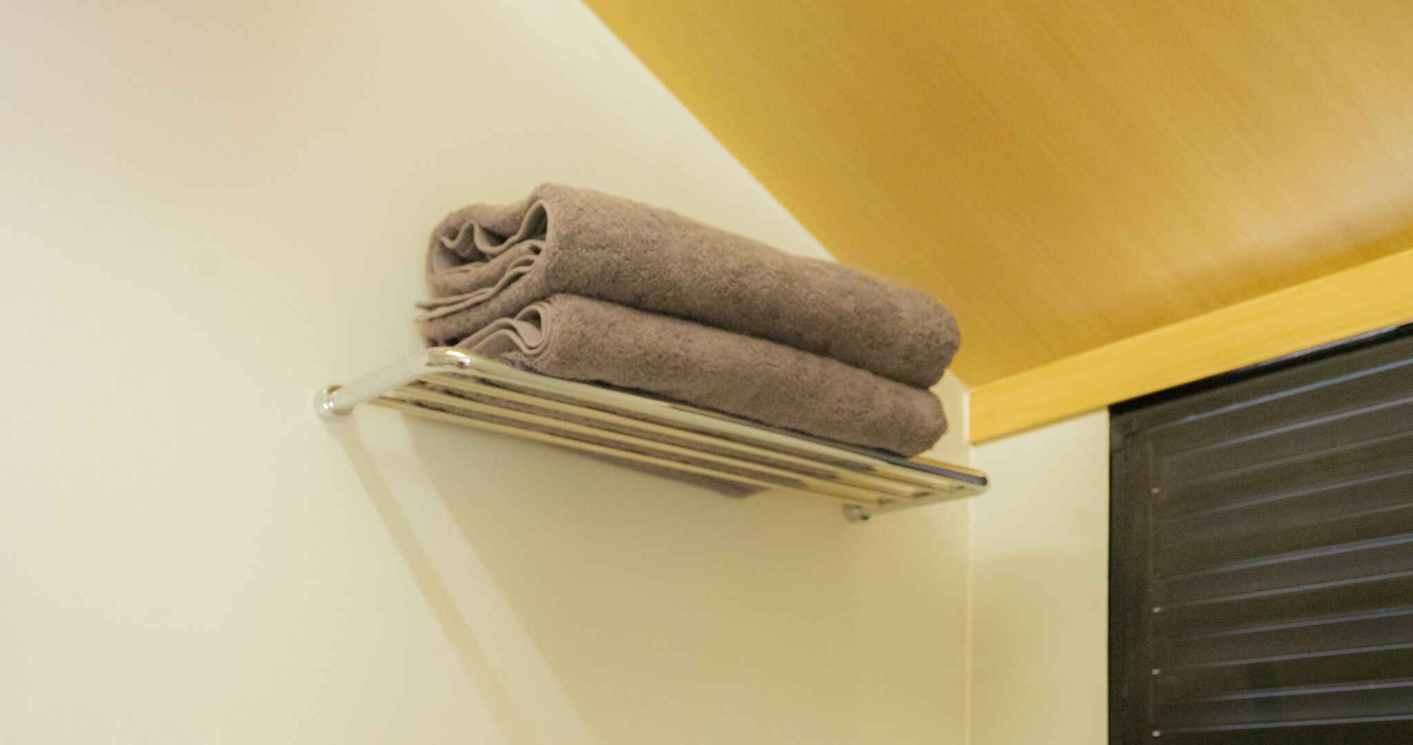 A towel rack with two folded towels against a wall.