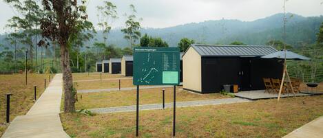 A campsite with a map sign, cabins, and a dining area.