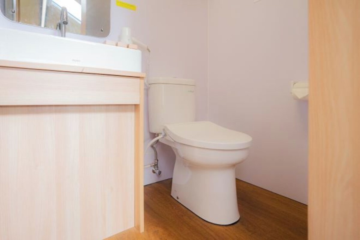 A small bathroom with a toilet, a sink, and a mirror.
