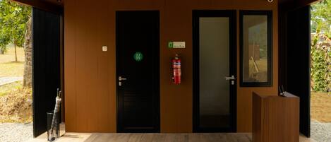 A modern entrance with two black doors, a fire extinguisher, and a wooden reception desk.