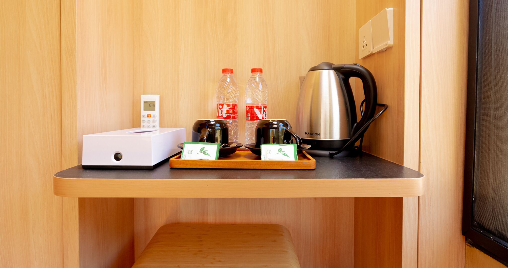 A compact kitchenette with a coffee maker, two bottles of water, a scale, and a small white appliance.
