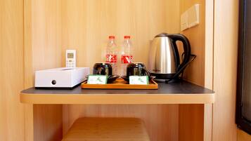 A compact kitchenette with a coffee maker, two bottles of water, a scale, and a small white appliance.
