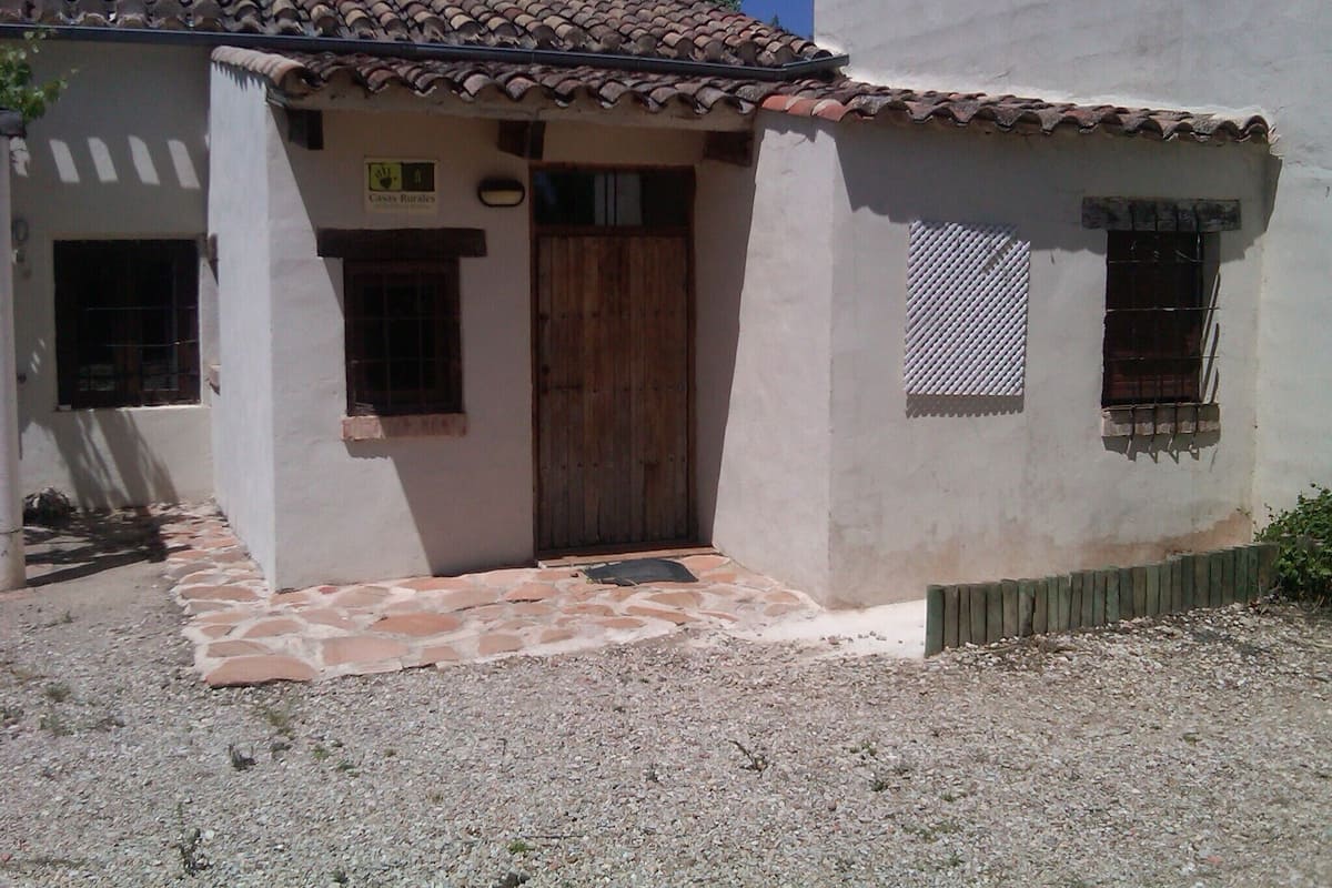 A rustic building with a tiled roof, a wooden door, and a small window with a metal grill.