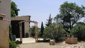 Une cour intérieure avec une arche en bois menant à un bâtiment, le tout entouré de chemins de gravier et de pierres.