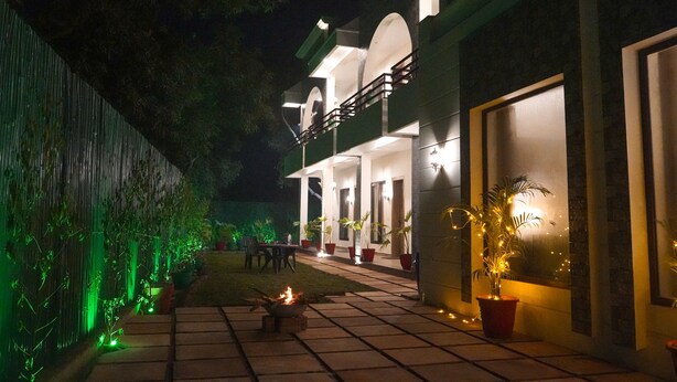 A two-story building with a covered patio area, outdoor seating, and potted plants. - Wild Pensione Resort  (Ramnagar)