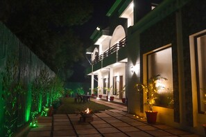 A two-story building with a covered patio area, outdoor seating, and potted plants.