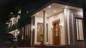 A building with a wooden door, columns, and potted plants. - Wild Pensione Resort  (Ramnagar)