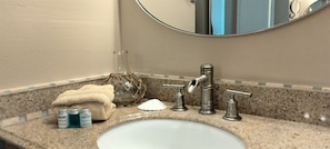 Bathroom features a granite countertop, a white sink, and a round mirror.