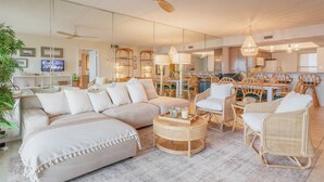 A spacious living area with a sofa, chairs, a dining table, and a ceiling fan.