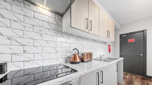 A modern kitchen with marble tiles, stainless steel appliances, and wooden cabinets. - Cozy Serviced En-suite Room Sydenham London Se26 (London)