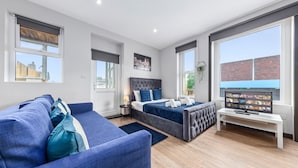 A modern bedroom with a bed, a TV, and a sofa. - Sleep 4 Serviced Ensuite Room Sydenham London Se26 (London)