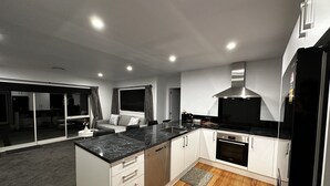A modern kitchen with white cabinets, a black countertop, and a built-in oven.