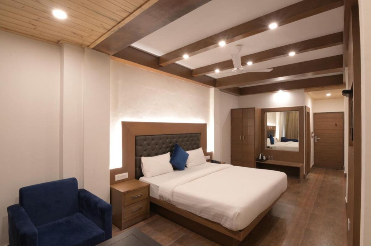 A modern bedroom with a large bed, a nightstand, a chair, and a wardrobe.