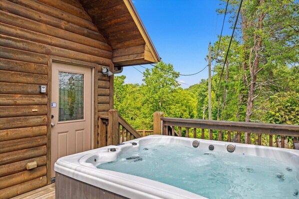 A wooden cabin with a hot tub on the deck.