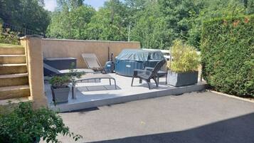 Une terrasse avec mobilier d’extérieur, un barbecue et un espace salon abrité.
