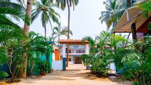 A tropical resort with a sandy pathway leading to a building with a tiled roof and a sign for 'Tropical Retreat'. - Dersy Beach Resort (Canacona)