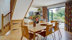 A dining area with a wooden table and chairs, a vase with flowers, and a staircase leading to an upper level.