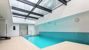 An indoor swimming pool with a glass ceiling, tiled walls, and a tiled floor. - Lovely Studio Close to the Wharf (Auckland)