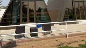 A modern building with triangular glass windows and a paved outdoor area with seating. - NIRVANA RETREAT (Ras Al Khaimah)