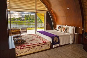 Una camera da letto con un ampio letto, vista su un lago e un soffitto in legno.