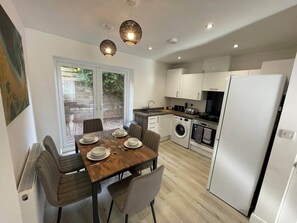 A compact kitchen with a dining area, a washing machine, and a refrigerator. - 3 Bedroom New House with WiFi (Newcastle-Under-Lyme)