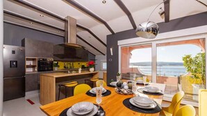 Una cocina moderna con comedor, ventanas amplias y vista al mar.