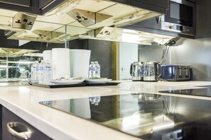 A modern kitchen with stainless steel appliances, a glass countertop, and a coffee maker. - Galore Abode One Bed Apartment  (London)